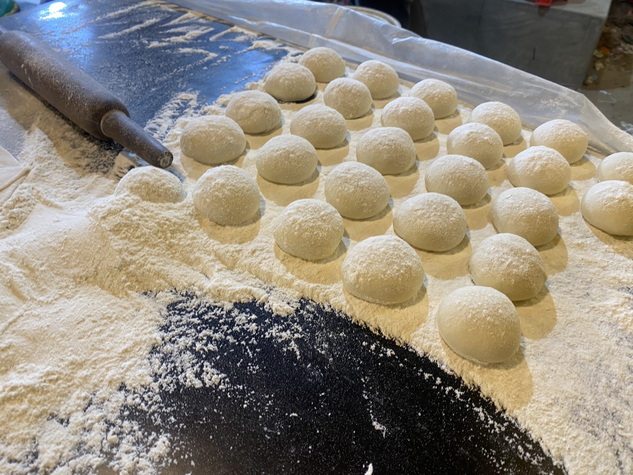 Rows of round dough balls covered in flour, resting before shaping