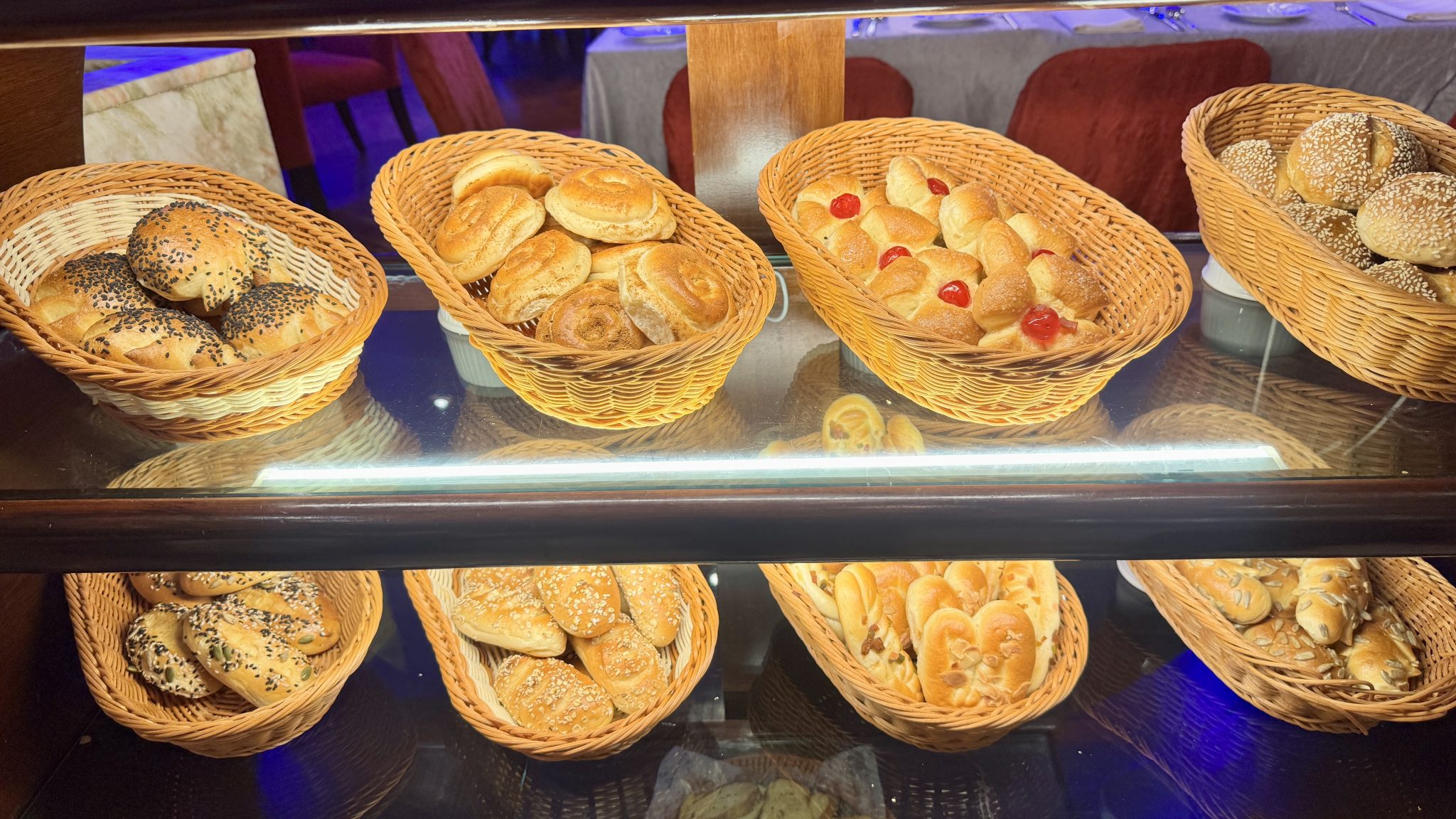 A bakery shelf of fresh bread rolls in baskets