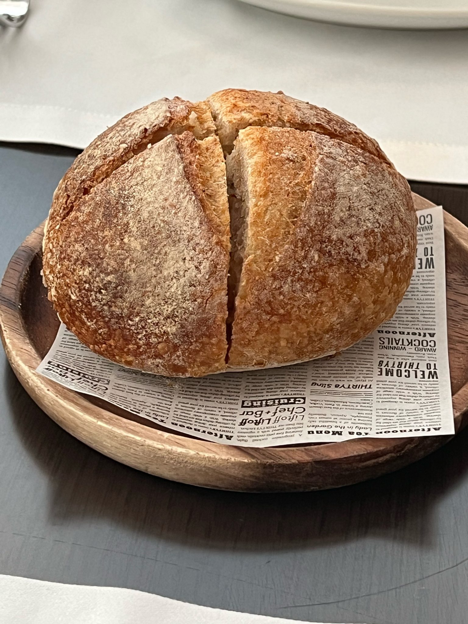 A round loaf with a cross cut into its crust on a wooden plate